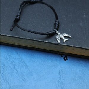 Adjustable bracelet with a bird pendant.